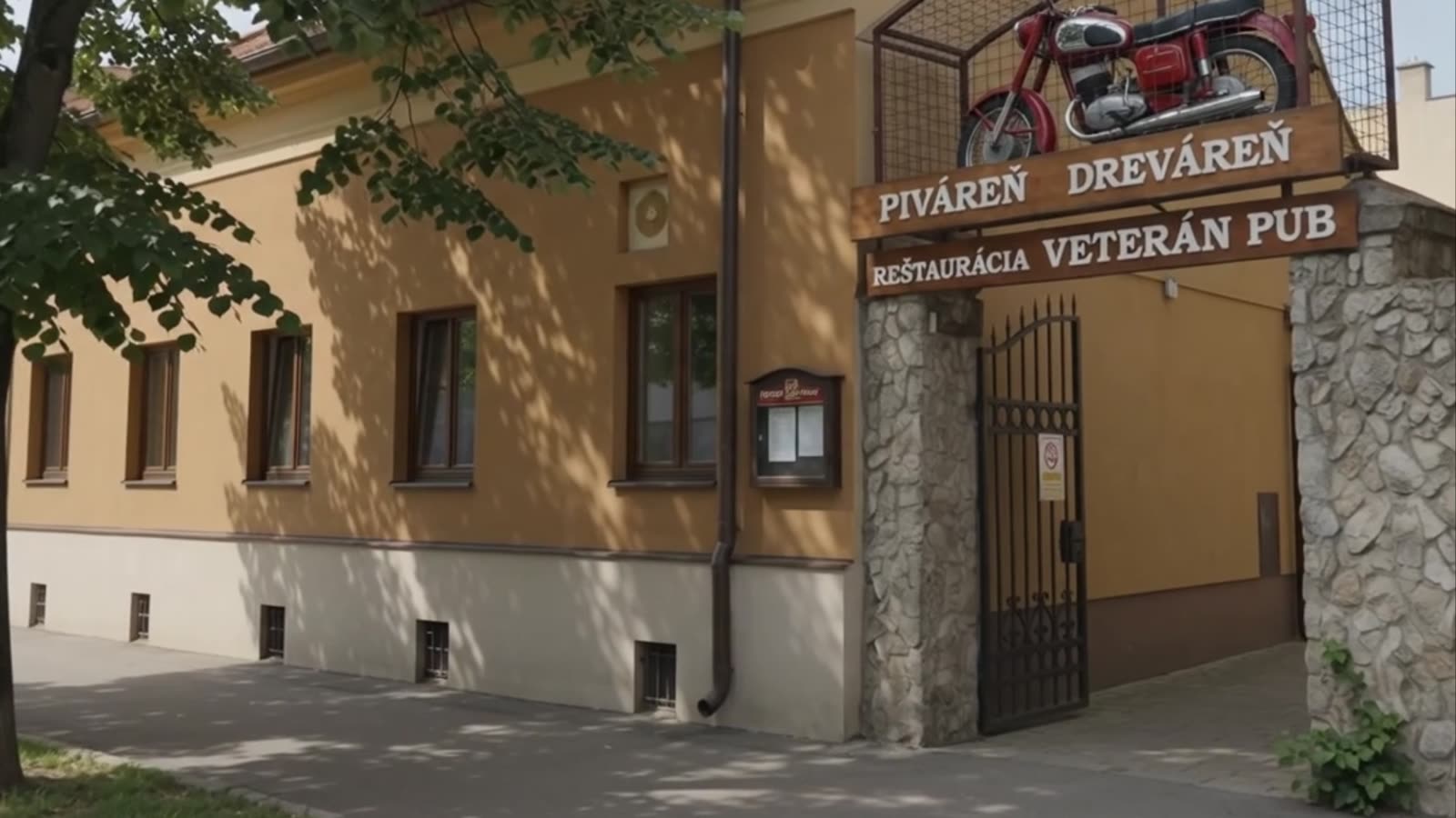 Vchod do Veterán Pubu so starou motorkou nad bránou